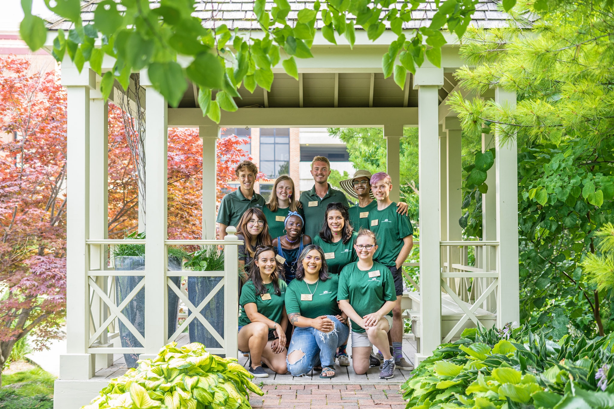 Smiling interns under a shade structure in the garden.