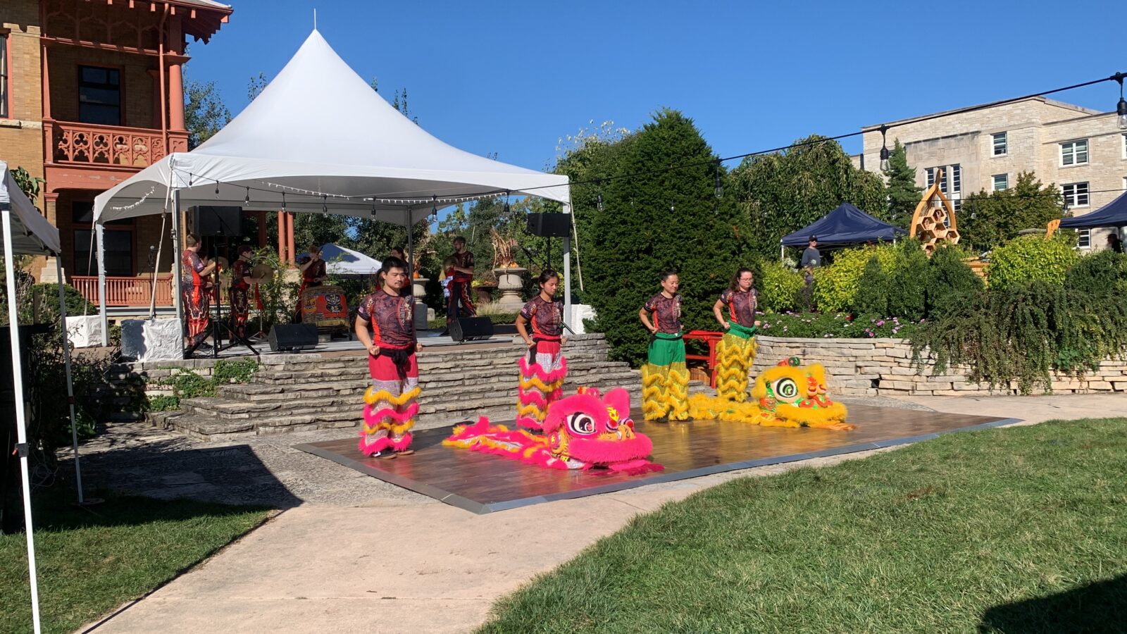 Lion dancers with costumes laid out in front of them on stage