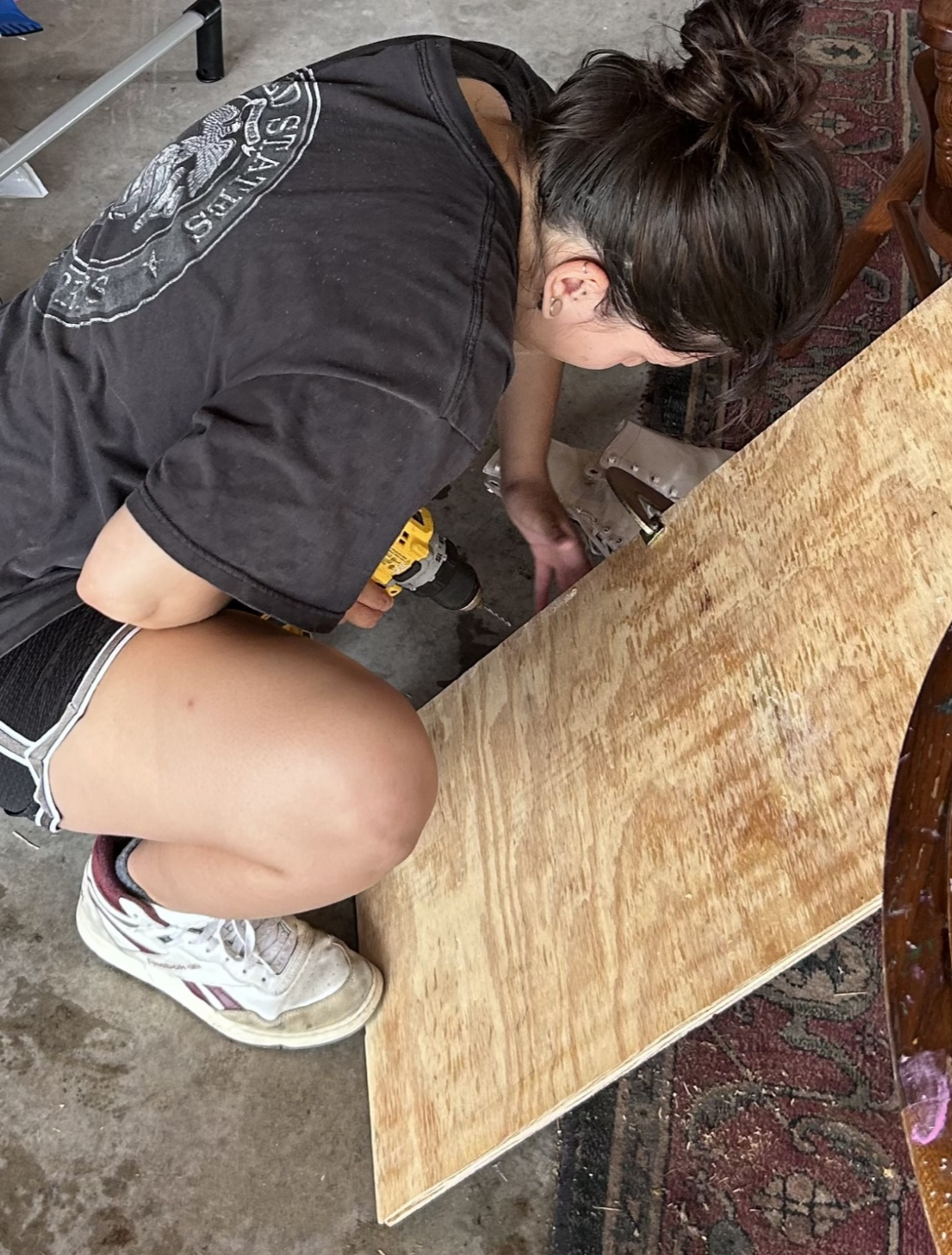 Eileen crouched in a garage in the process of screwing the bat box together.